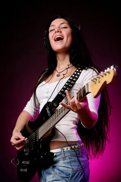 Ragazza sorridente felice che gioca chitarra