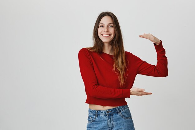 Ragazza sorridente fiera che modella grande scatola, grande oggetto