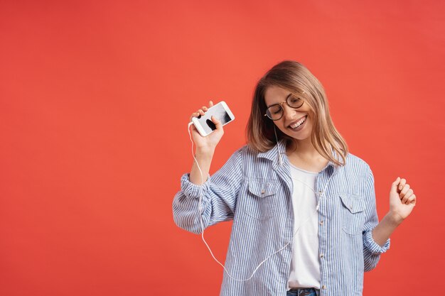 Ragazza sorridente in abbigliamento casual e cuffie che ballano le mani commoventi.