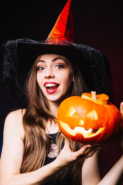 Ragazza sorridente in cappello da strega con zucca