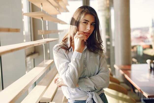 Ragazza sorridente in una camicia blu che sta finestra vicina