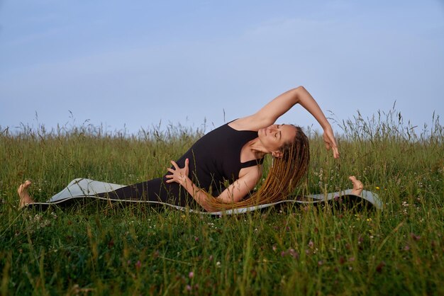 Ragazza sorridente sanguinante che fa fasciatura laterale sulla stuoia di yoga