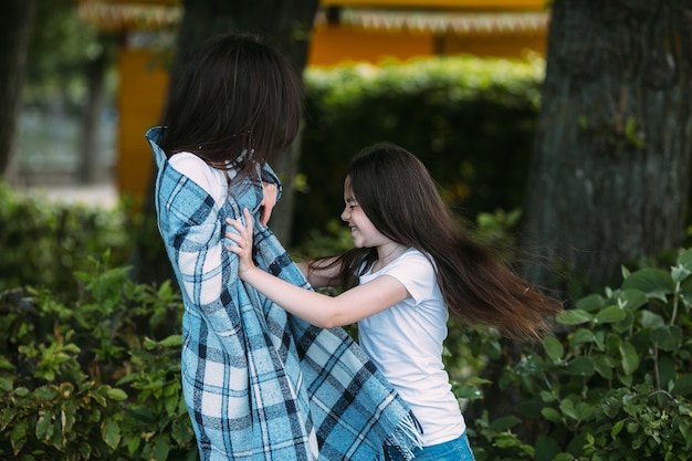 Ragazza sorridente spingendo donna avvolto in plaid