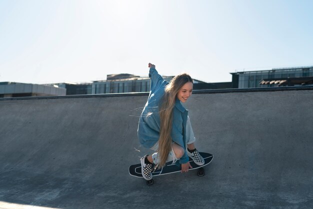 Ragazza sorridente su skateboard vista laterale all'aperto