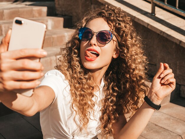 Ragazza spensierata che si siede sulle scale in strada prendendo un selfie