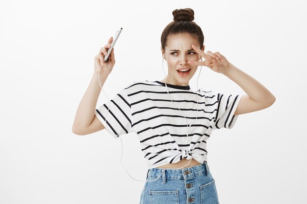 Ragazza spensierata in auricolari che balla, ascolta musica sull'app mobile in streaming