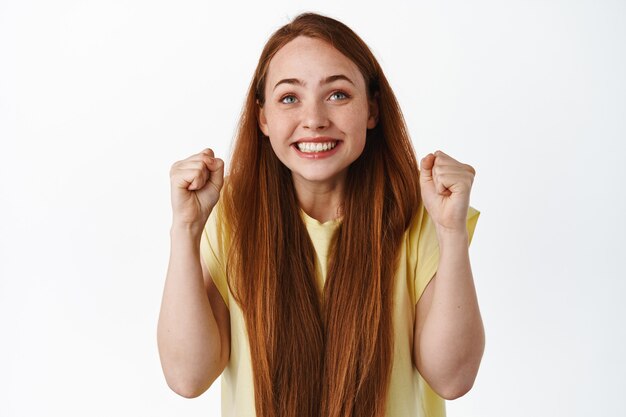 ragazza speranzosa che guarda lo schermo con i pugni chiusi e una faccia sorridente eccitata scommette su bianco.