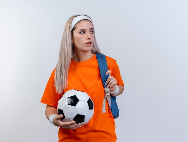 Ragazza sportiva caucasica giovane infastidita con le parentesi graffe che portano la fascia ed i braccialetti dello zaino