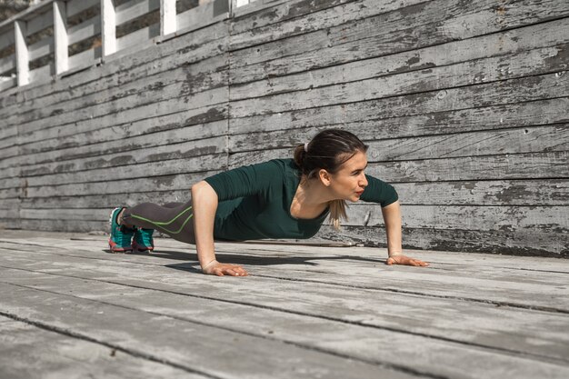 ragazza sportiva fitness in abiti sportivi sta facendo esercizi su uno sfondo di legno, sfondo chiaro, il concetto di sport