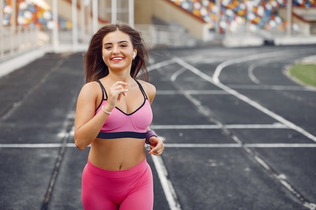 Ragazza sportiva in uniforme rosa corre allo stadio