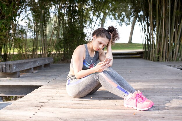 Ragazza sportiva serio ascoltando musica nel parco