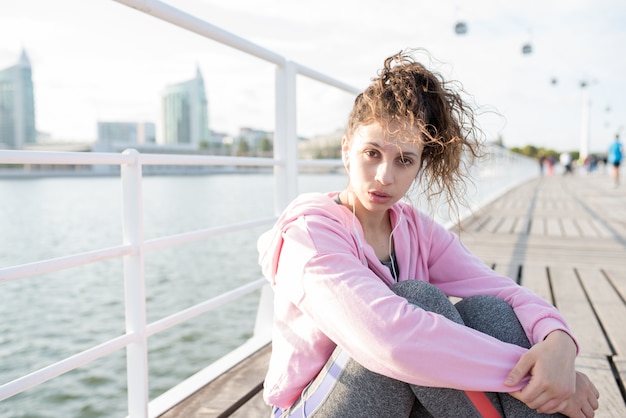 Ragazza sportiva serio ascoltando musica sul banco