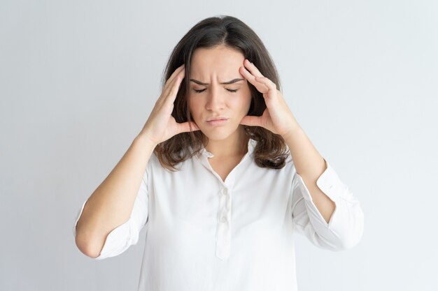 Ragazza stanca frustrata che soffre di mal di testa.