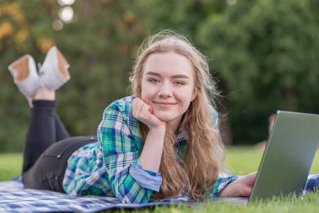 Ragazza studiando con il portatile sul panno da picnic