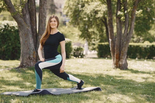 Ragazza sveglia che fa yoga in un parco di estate