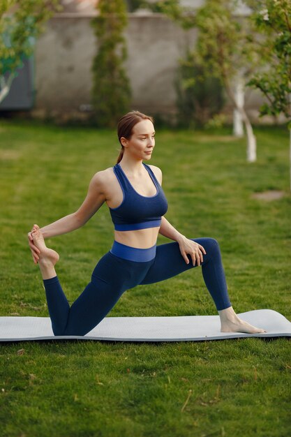 Ragazza sveglia che fa yoga in un parco di estate