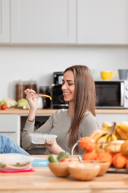 Ragazza sveglia che osserva e che sorride al suo alimento