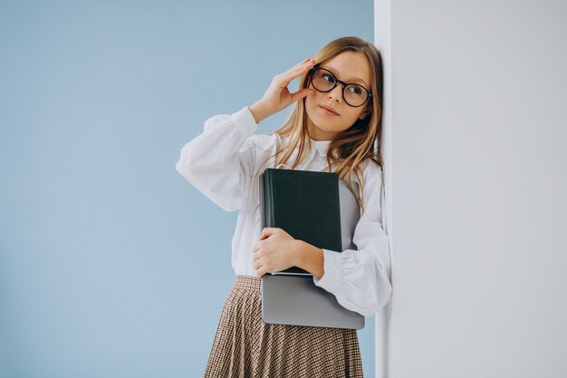 Ragazza sveglia che tiene libro e laptop in ufficio