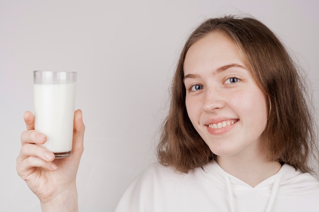 Ragazza sveglia di vista frontale che tiene un bicchiere di latte