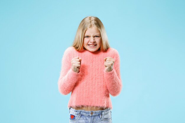 Ragazza teenager arrabbiata che sta sullo studio blu alla moda.