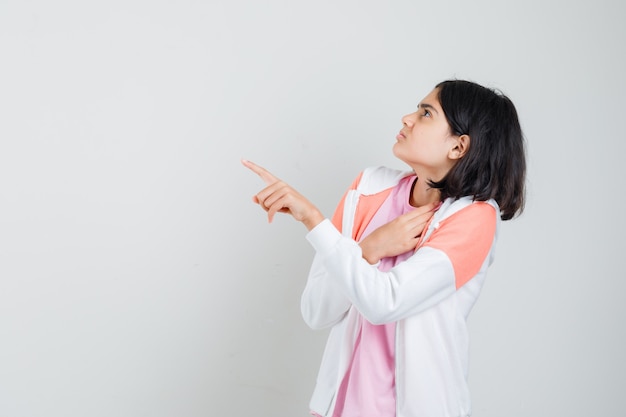 Ragazza teenager che indica qualcuno in giacca, camicia rosa e sembra disgustata.