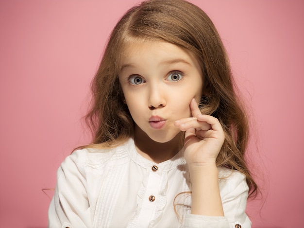 Ragazza teenager divertente felice isolata sulla parete rosa alla moda. Bellissimo ritratto femminile. Ragazza del bambino piccolo. Emozioni umane, concetto di espressione facciale. Vista frontale.