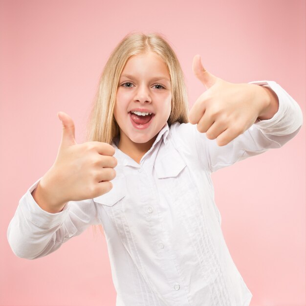 Ragazza teenager felice in piedi, sorridente isolato su sfondo rosa alla moda per studio. Bellissimo ritratto femminile. I giovani soddisfano la ragazza con il segno ok.