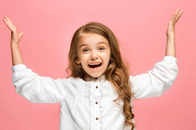 Ragazza teenager felice in piedi, sorridente isolato su sfondo rosa alla moda per studio.