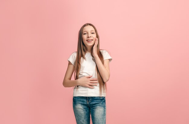 Ragazza teenager felice in piedi, sorridente isolato su studio rosa alla moda