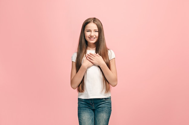 Ragazza teenager felice in piedi, sorridente isolato su studio rosa alla moda