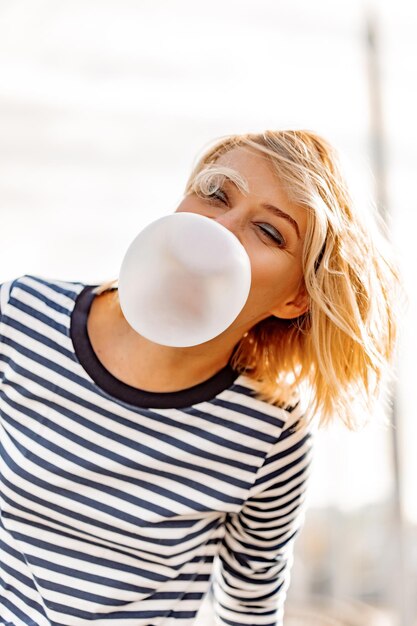 Ragazza urbana alla moda. Ritratto emotivo all'aperto del modello di donna attiva. Uno stile di vita sano. Look alla moda, ritratto hipster all'aperto. Close up ritratto di una bella ragazza che mastica gomma da masticare.