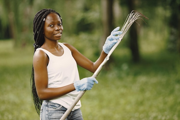 Ragazza volontaria che si prepara per il lavoro, tiene in mano il rastrello e lo controlla