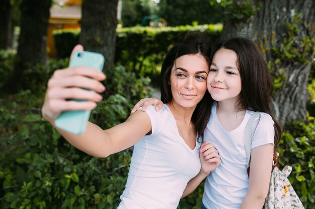 Ragazze abbracciando in piedi selfie