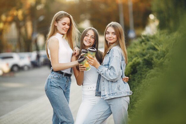 Ragazze che camminano in una città di primavera e prendendo il caffè