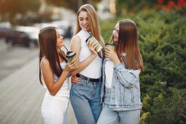 Ragazze che camminano in una città di primavera e prendendo il caffè