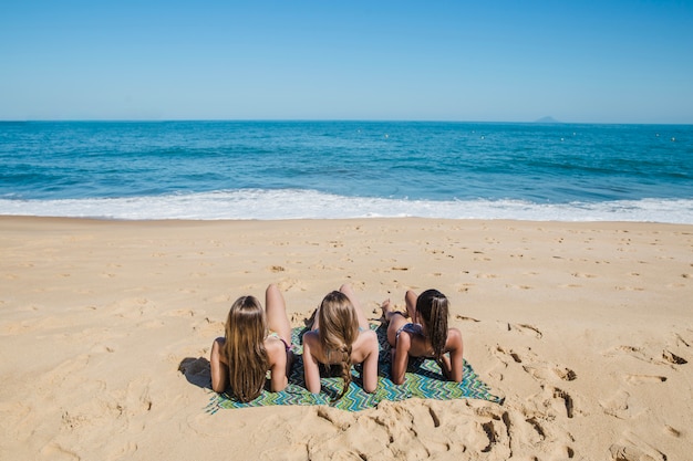 Ragazze che giace sulla sabbia