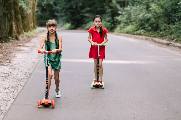 Ragazze che godono in sella a scooter su strada