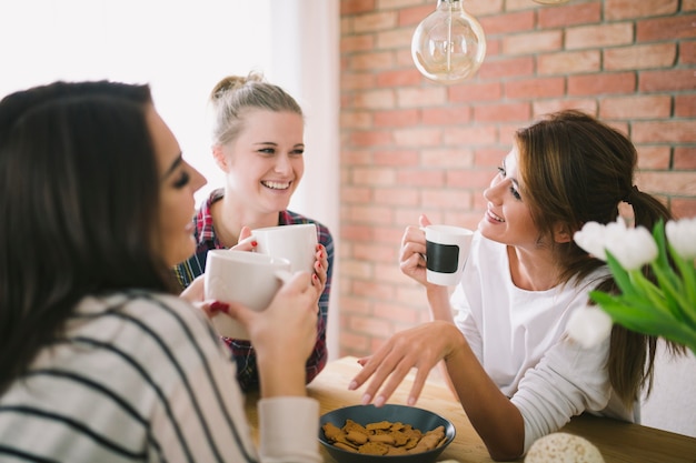 Ragazze che ridono bevendo tè e parlando