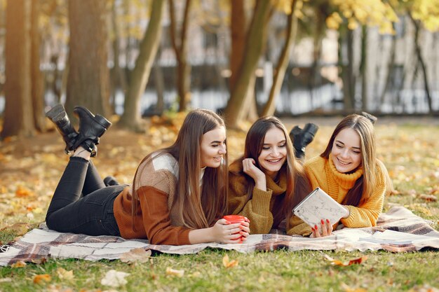 Ragazze che si siedono su una coperta in un parco di autunno