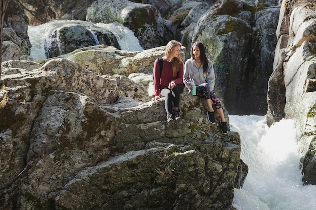 Ragazze che si siedono su una roccia e parlando