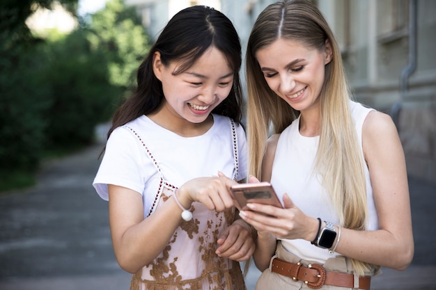 Ragazze del colpo medio che sorridono al telefono