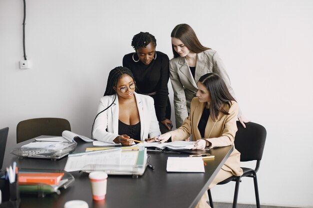 Ragazze di impiegati multirazziali che lavorano insieme seduto alla scrivania. Discutendo il progetto di affari