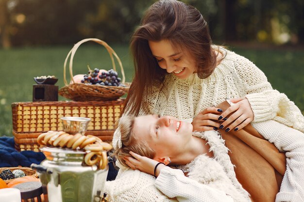 Ragazze eleganti e alla moda che si siedono in un parco di autunno