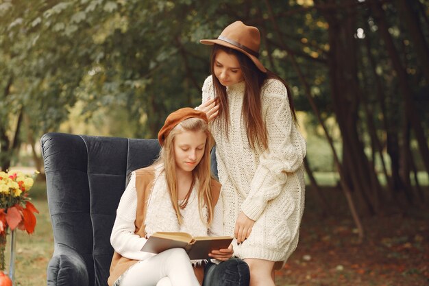 Ragazze eleganti e alla moda, seduto su una sedia in un parco