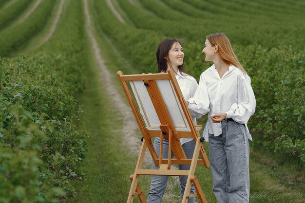 Ragazze eleganti e belle che dipingono in un campo