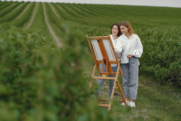 Ragazze eleganti e belle che dipingono in un campo