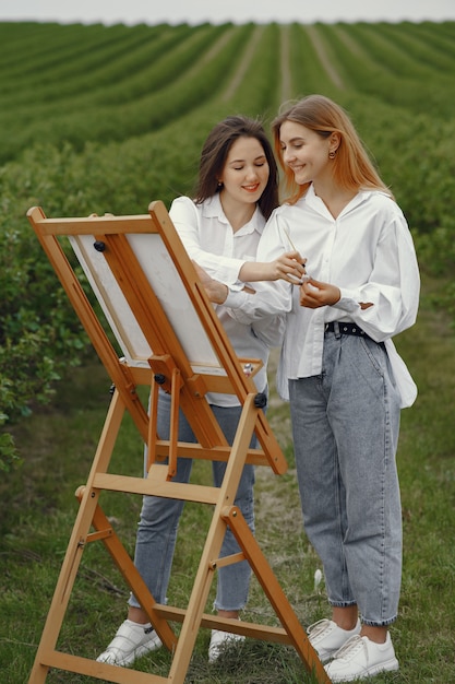 Ragazze eleganti e belle che dipingono in un campo