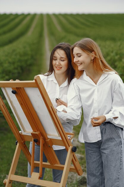 Ragazze eleganti e belle che dipingono in un campo