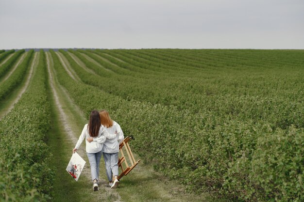 Ragazze eleganti e belle che dipingono in un campo