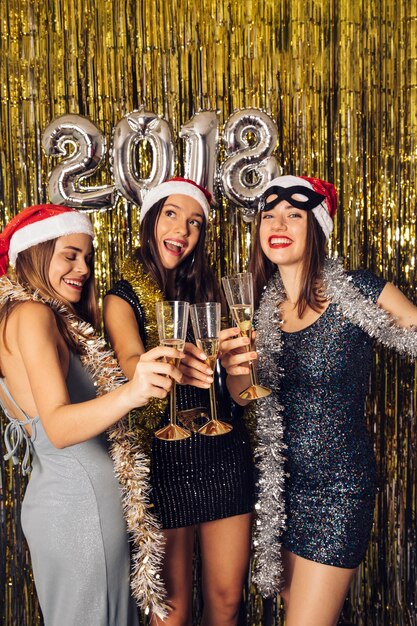 Ragazze in posa con champagne sul partito di nuovo anno